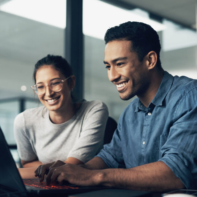 Two people working on a laptop in a global office.