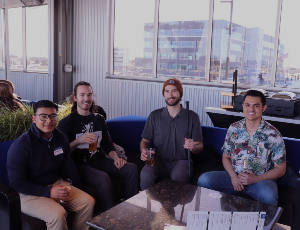 A group of men sitting on a couch at a careers fair.